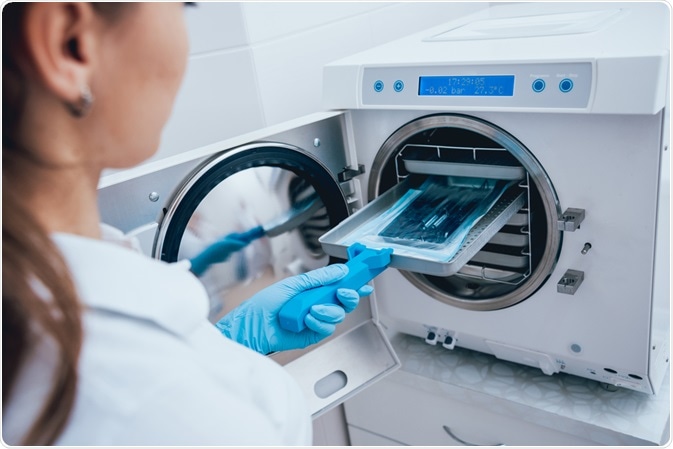 Dentist inserting medical utensils into autoclave machine