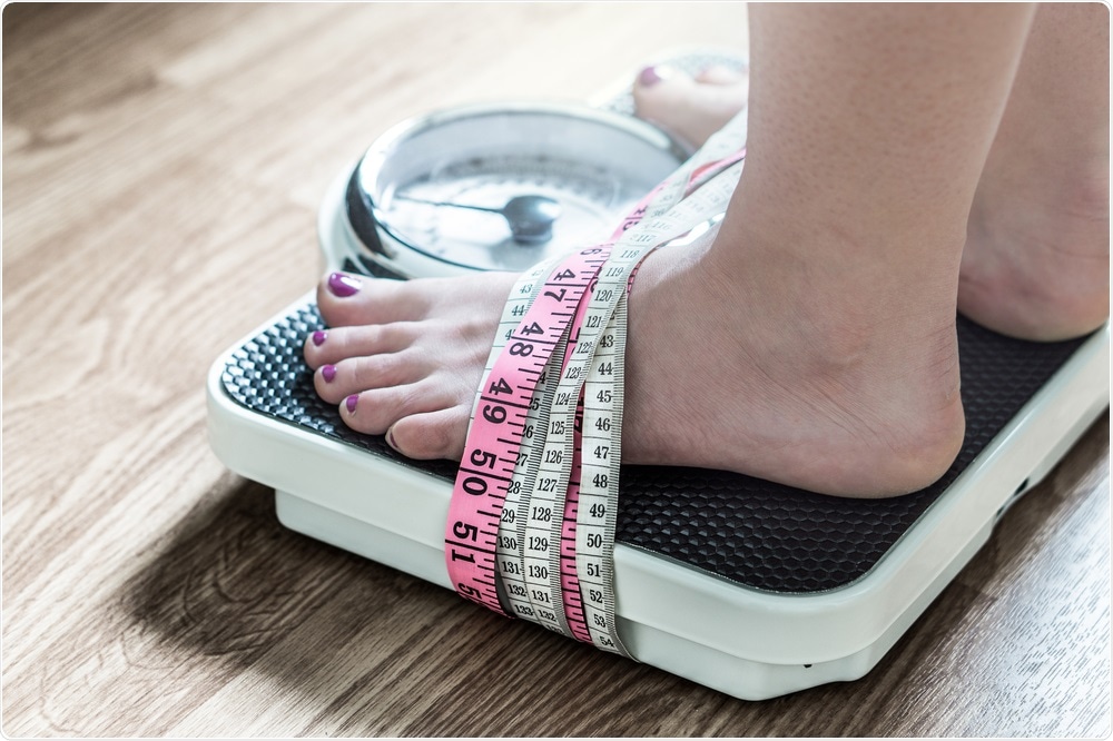 Woman stood on weighing scale.