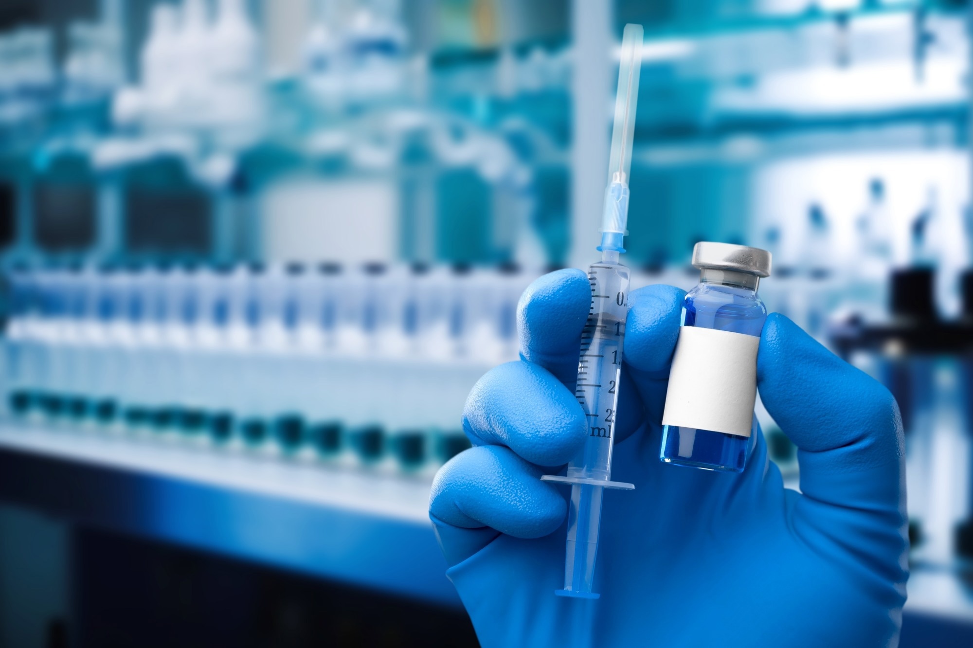 Gloved hand of medical professional holding vaccine syringe and vial