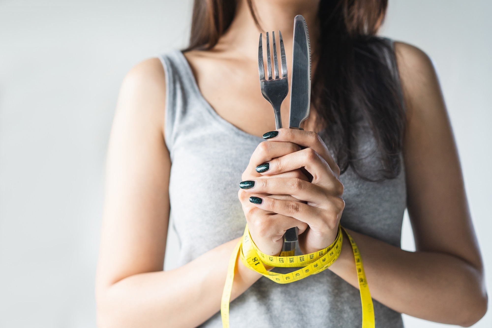 Woman holding a knife and for with hands tied together with a tape measure