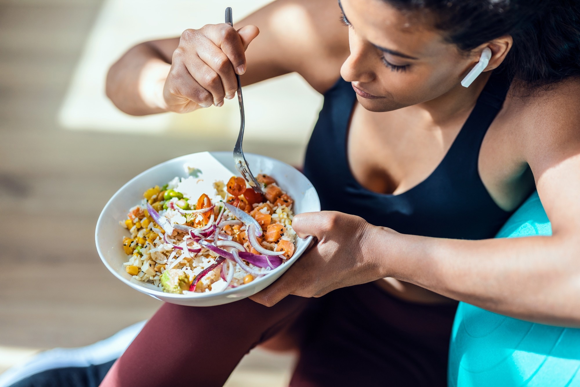 sporty young woman eating a bowl of vegan salad