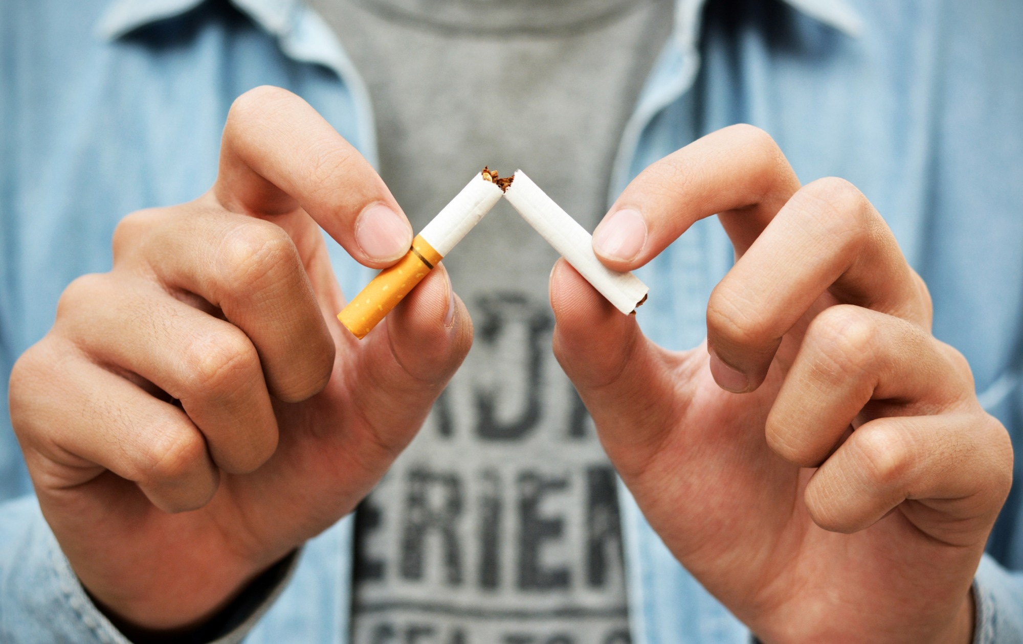 Close up of mans hands snapping a cigarette